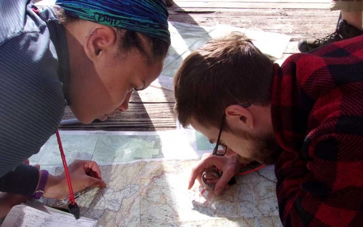 Two people lean forward over a map as they examine it closely. 